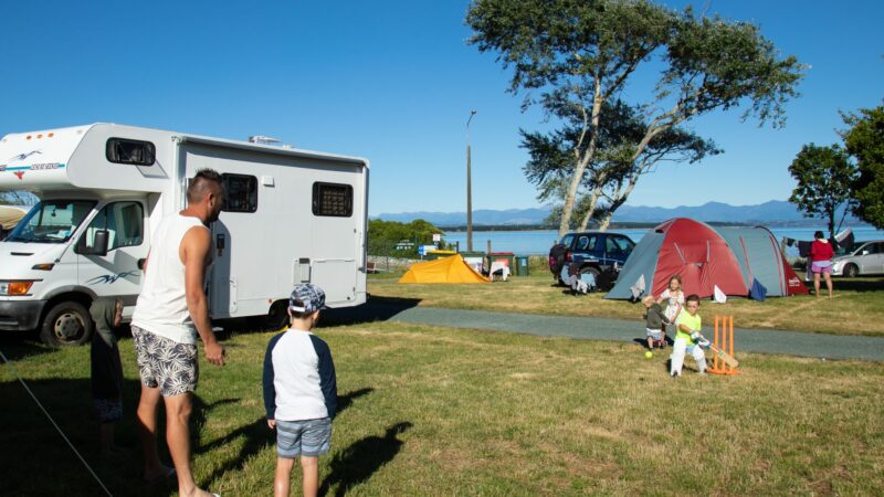 Family playing cricket while camping