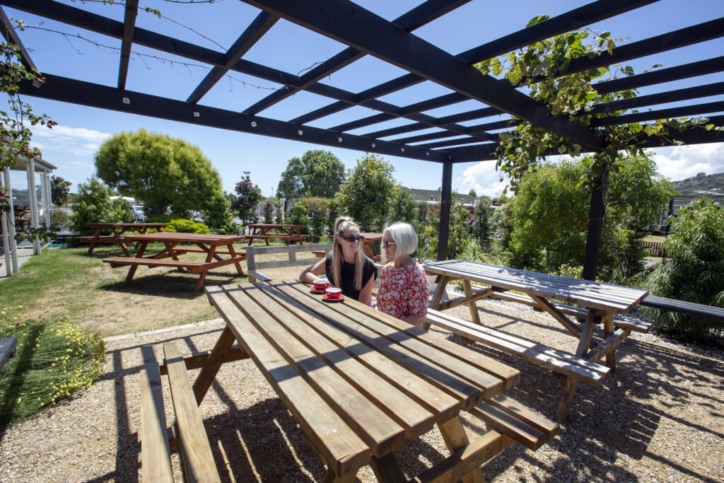 People drinking coffee in the garden by The Deck Cafe